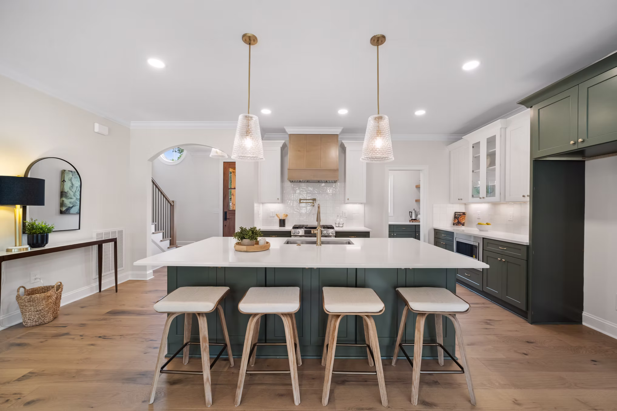 New construction kitchen with a green island and two brass pendant lights sized correctly over the island, sold by The Lighting Loft